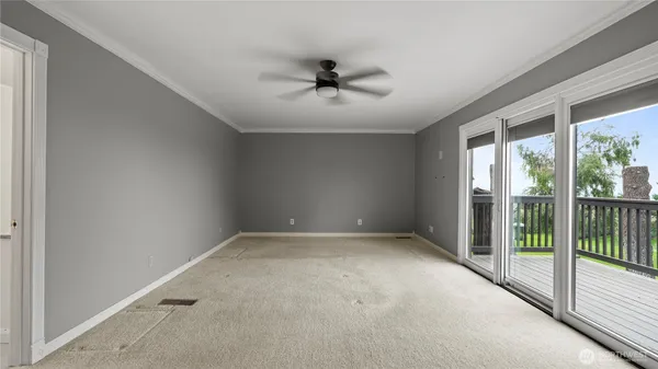 an empty room with a ceiling fan and windows