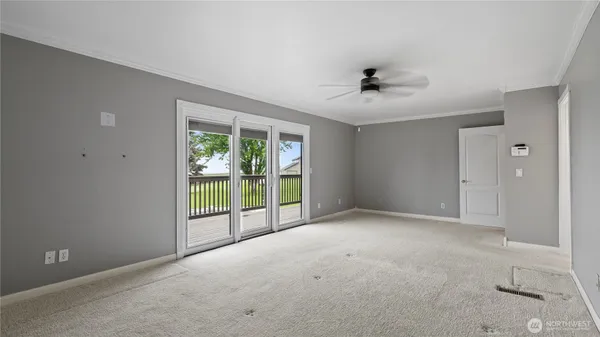 an empty room with windows and chandelier fan