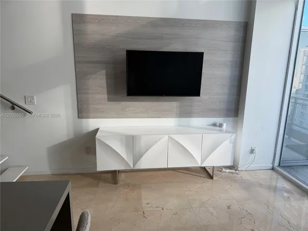 a living room with stainless steel appliances kitchen island furniture and a flat screen tv