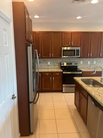 a kitchen with kitchen island granite countertop a sink a counter top space a stove and cabinets