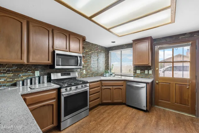 a kitchen with stainless steel appliances granite countertop wooden cabinets granite counter tops and a window