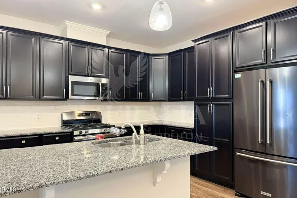 a kitchen with stainless steel appliances granite countertop a refrigerator a stove and a sink with wooden cabinets
