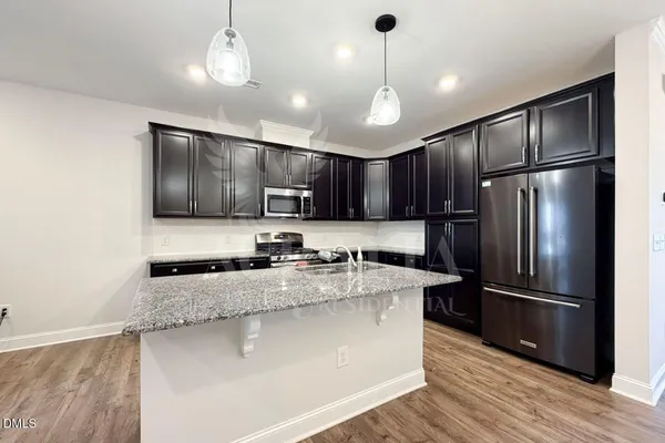 a kitchen with stainless steel appliances granite countertop a refrigerator a sink dishwasher a stove and a refrigerator with wooden floor