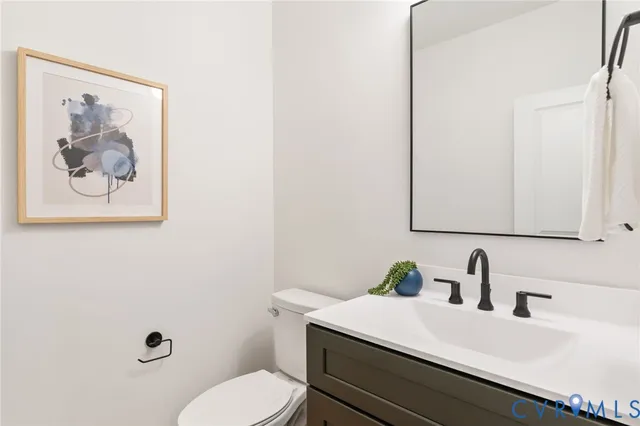 a bathroom with a granite countertop sink mirror vanity and toilet