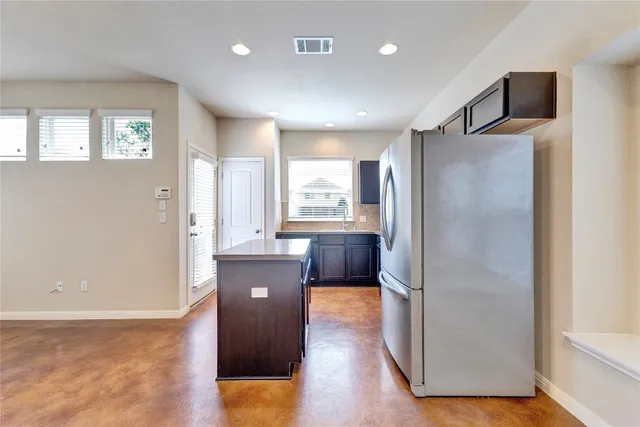 a kitchen with kitchen island wooden floor and refrigerator