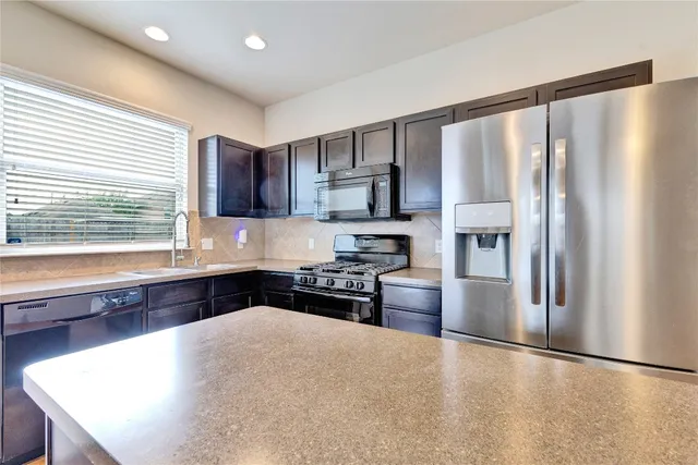 a kitchen with stainless steel appliances a refrigerator sink and stove