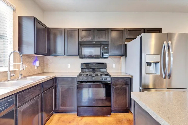 a kitchen with stainless steel appliances granite countertop a stove a refrigerator and a sink