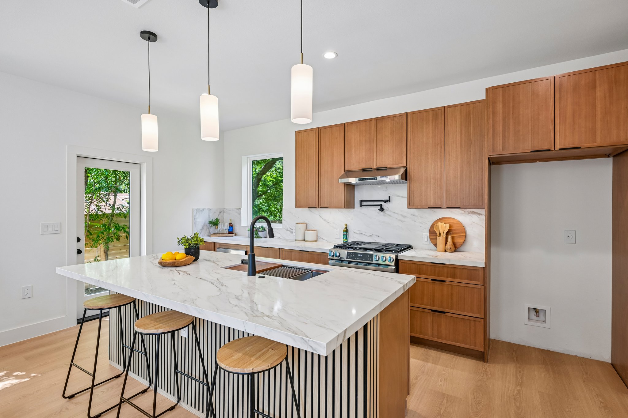 513 West Odell Street, Unit B Austin, TX 78752 - Photo 11 of 38 Modern kitchen with large island, sleek wooden cabinetry, pot filler and stainless steel appliances.