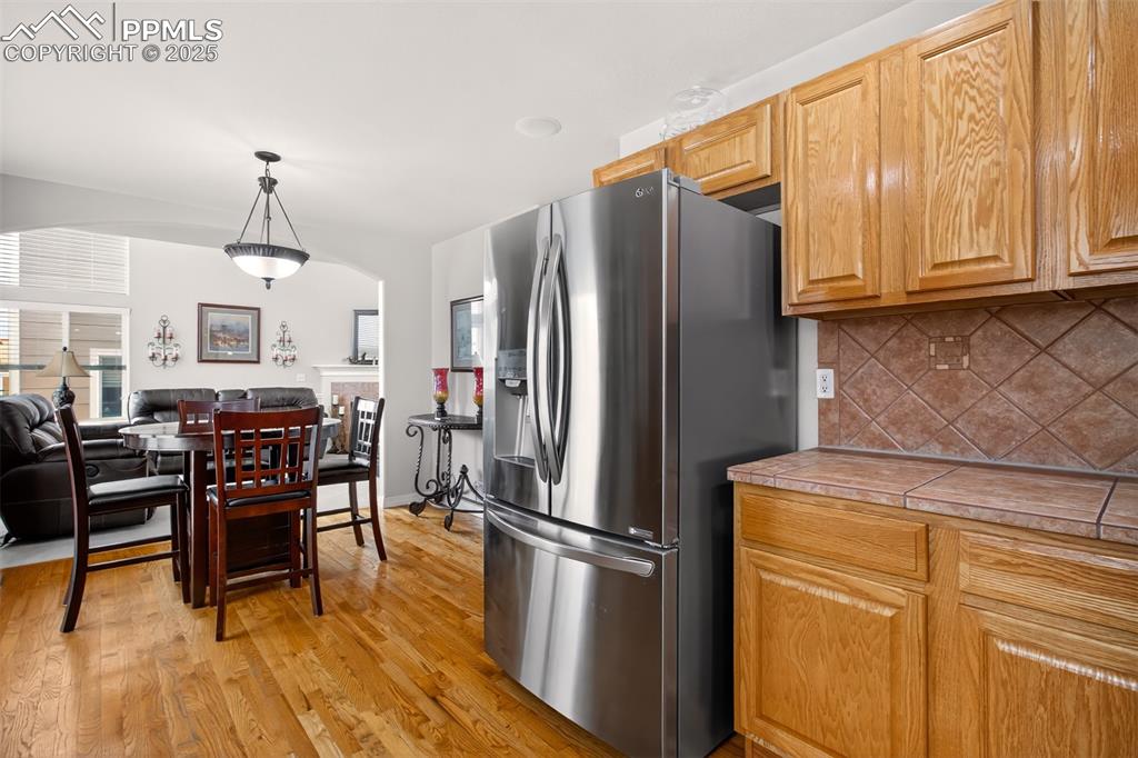 7374 Maybeck View Peyton, CO 80831 - Photo 5 of 38 a kitchen with stainless steel appliances granite countertop a refrigerator a stove a dining table and chairs with wooden floor