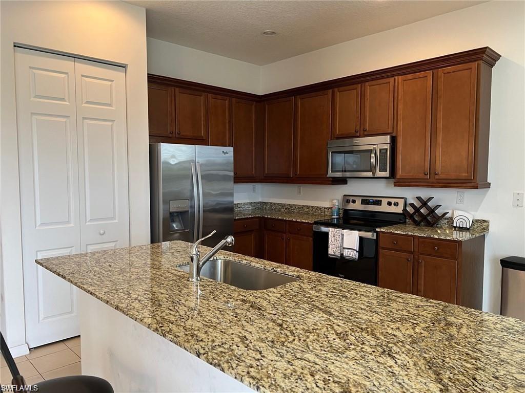 5293 Beckton Road Ave Maria, FL 34142 - Photo 11 of 17 a kitchen with kitchen island granite countertop a sink stove and refrigerator