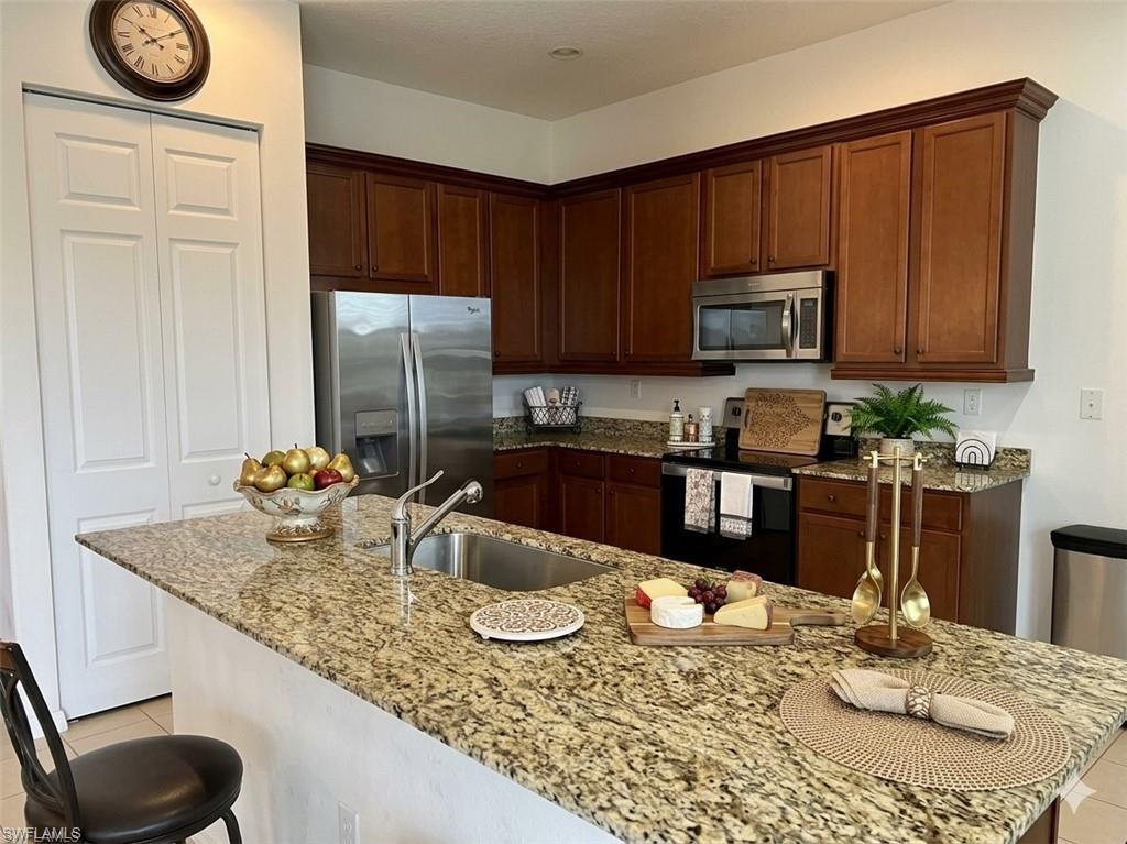 5293 Beckton Road Ave Maria, FL 34142 - Photo 3 of 17 a kitchen with granite countertop stainless steel appliances a sink a stove a microwave a dining table and chairs