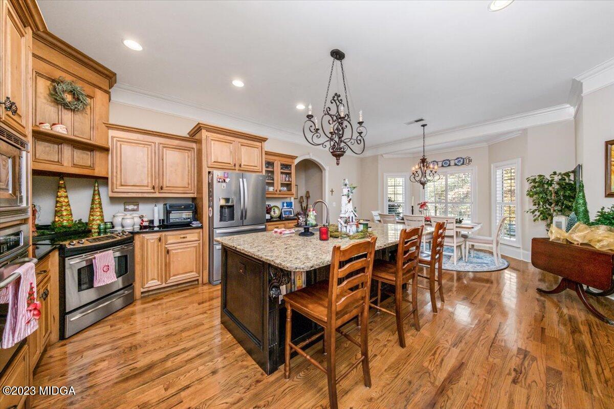 60 Walden Road Forsyth, GA 31029 - Photo 7 of 31 a open kitchen with stainless steel appliances granite countertop a refrigerator a stove top oven a dining table and chairs with wooden floor
