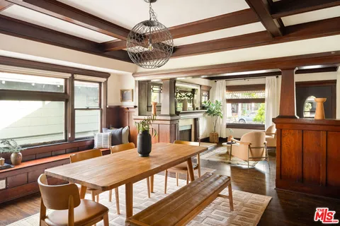 a dining room with wooden floor a chandelier fan a wooden table and chairs