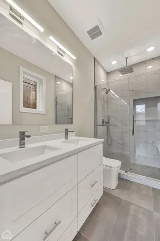 a bathroom with a double vanity sink toilet and shower
