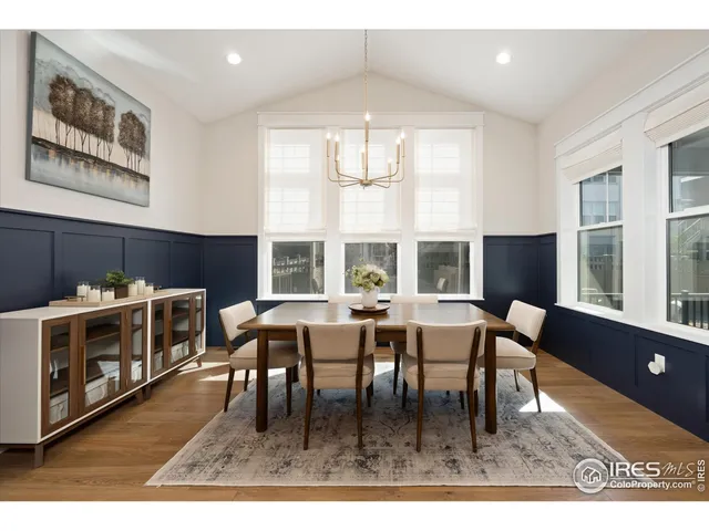 a dining room with furniture a floor to ceiling window and a wooden floor