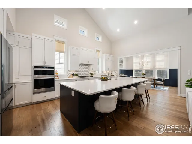 a kitchen with stainless steel appliances kitchen island granite countertop a table chairs sink and cabinets