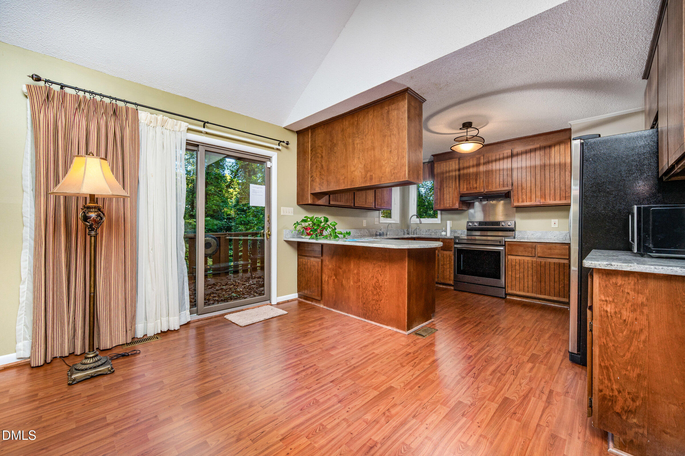 2900 Sylvania Drive Raleigh, NC 27607 - Photo 15 of 36 a kitchen with stainless steel appliances granite countertop a refrigerator a sink dishwasher a stove and a dining table with wooden floor