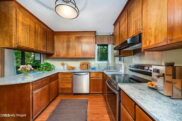 a kitchen with stainless steel appliances granite countertop wooden cabinets a sink and a stove