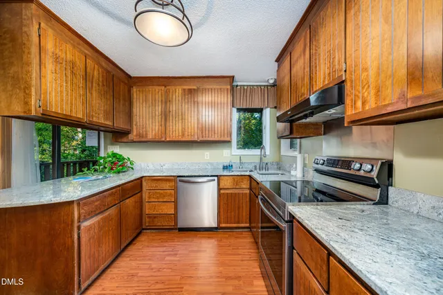 a kitchen with stainless steel appliances granite countertop a stove a sink and a refrigerator
