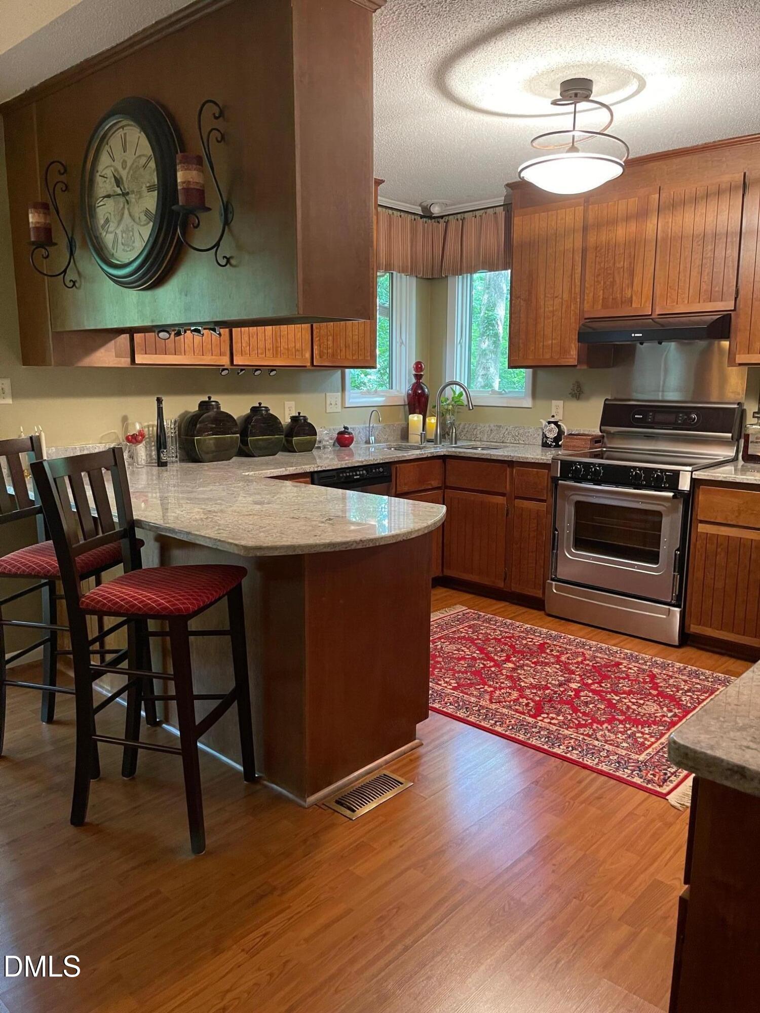 2900 Sylvania Drive Raleigh, NC 27607 - Photo 25 of 49 a kitchen with stainless steel appliances granite countertop a stove a sink dishwasher and a microwave with wooden floor
