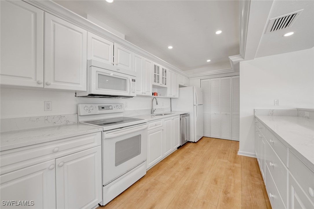 Undisclosed Address Sanibel, FL 33957 - Photo 12 of 30 a kitchen with white cabinets and white appliances