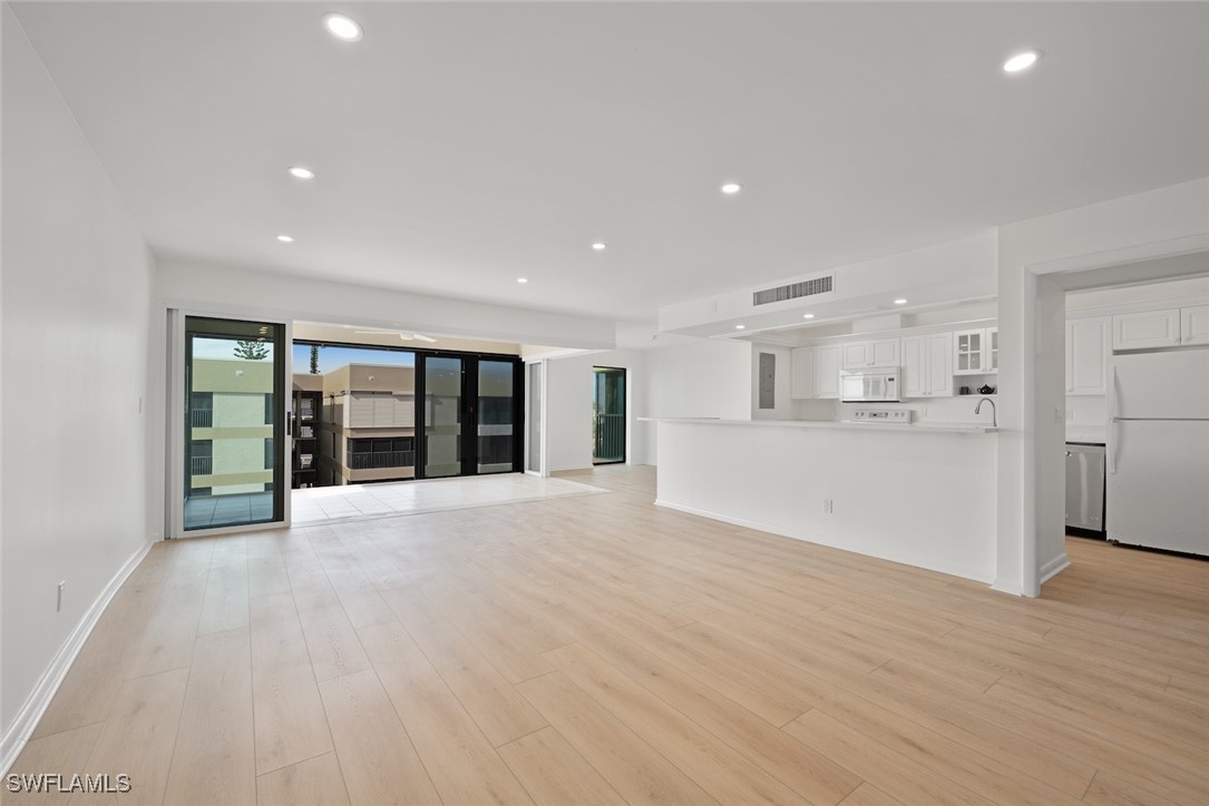 Undisclosed Address Sanibel, FL 33957 - Photo 4 of 30 a view of an empty room with wooden floor and a kitchen
