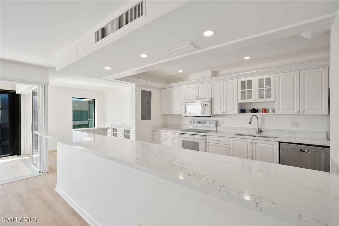 Undisclosed Address Sanibel, FL 33957 - Photo 9 of 30 a large white kitchen with kitchen island a large counter top space a sink stainless steel appliances and cabinets