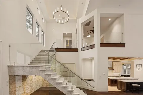 a view of an empty room and kitchen with wooden floor