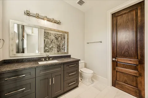 a bathroom with a granite countertop toilet sink and mirror