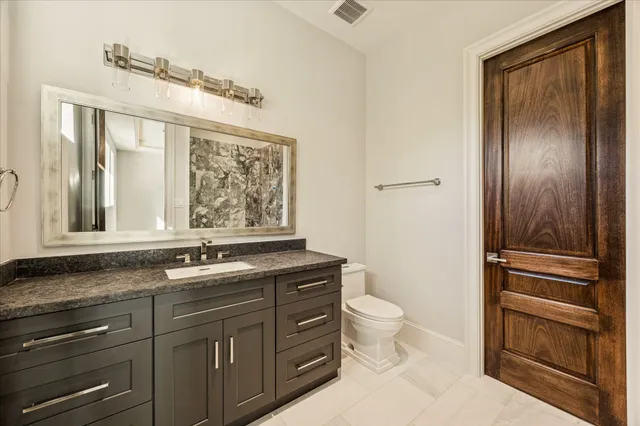 a bathroom with a granite countertop toilet sink and mirror