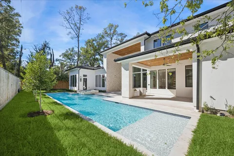 a view of a white house with a yard and table and chairs under an umbrella