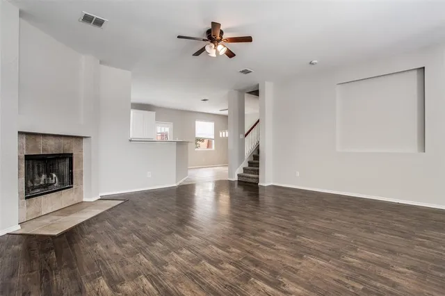 a view of an empty room with a fireplace and a chandelier fan