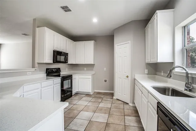 a kitchen with a sink a stove top oven and white cabinets