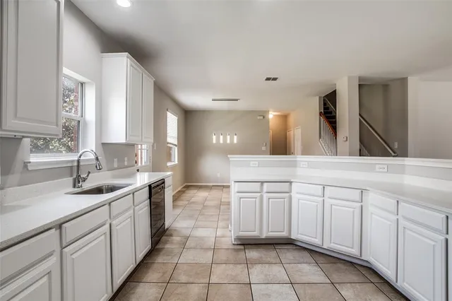 a large white kitchen with a sink and dishwasher