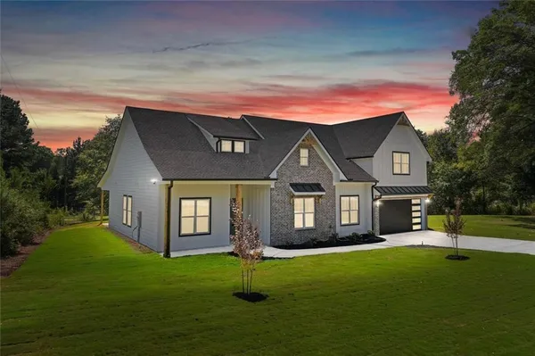 a front view of a house with a garden and trees