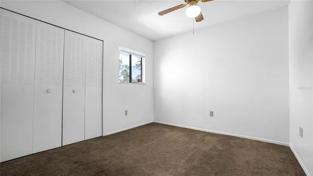 an empty room with windows and ceiling fan view