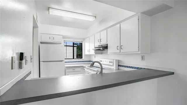 a kitchen with stainless steel appliances a sink a stove and white cabinets