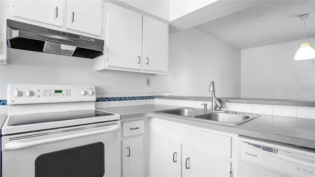 a kitchen with a stove white cabinets and a sink