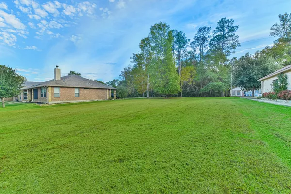 a white house with a big yard and large trees