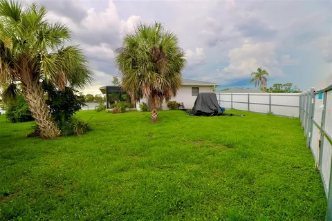 a view of a house with a yard and palm trees
