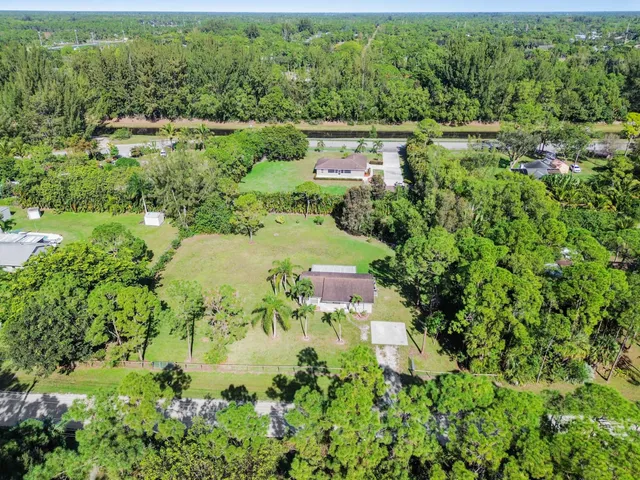 an aerial view of residential house with outdoor space and trees all around