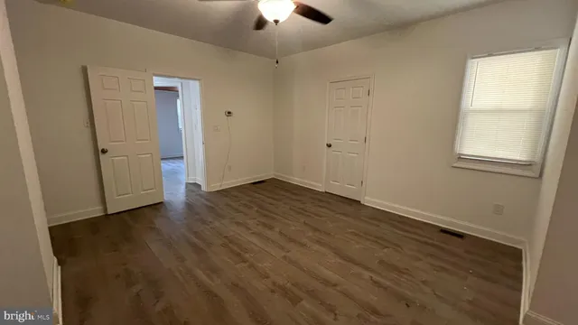 an empty room with wooden floor chandelier fan and windows