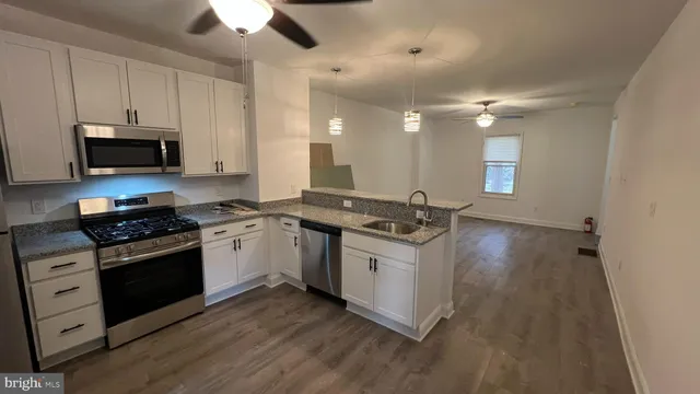 a kitchen with stainless steel appliances a sink a stove top oven a counter space and cabinets