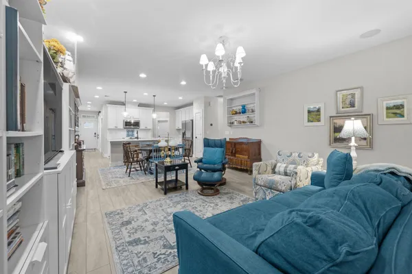 a living room with furniture kitchen view and a chandelier