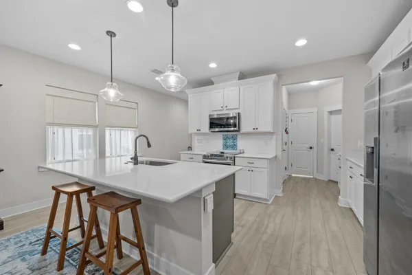 a kitchen with a sink a center island stainless steel appliances and cabinets