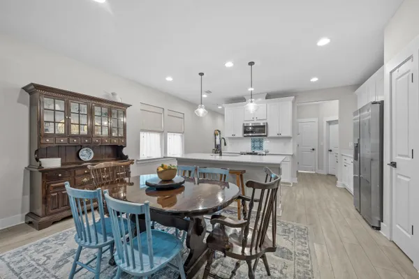 a kitchen with a dining table chairs refrigerator and cabinets