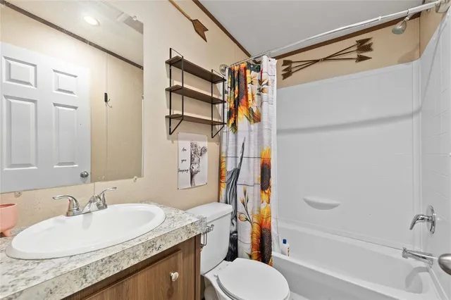 a bathroom with a granite countertop sink a toilet a mirror and shower
