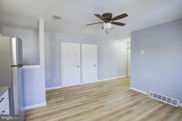 a view of empty room with wooden floor and ceiling fan