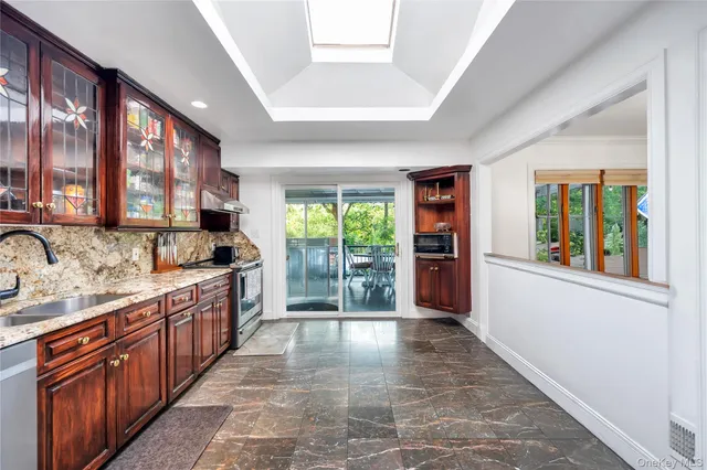 a large kitchen with stainless steel appliances granite countertop a large counter top a stove a chimney a sink and dishwasher