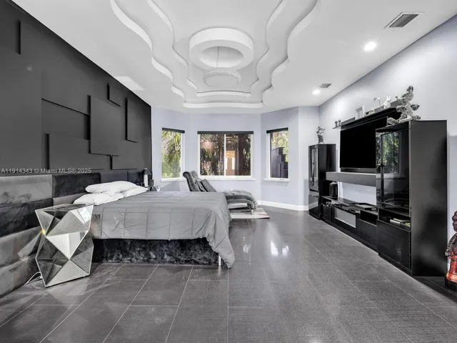 a bedroom with a large bed and a chandelier fan